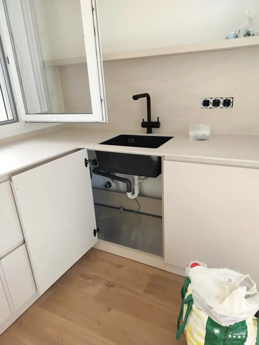 Fregadero de cocina instalado con grifo negro y desagüe bajo el mueble